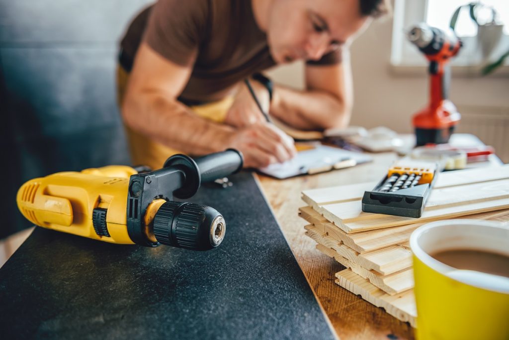 Man measuring a piece of wood before drilling it