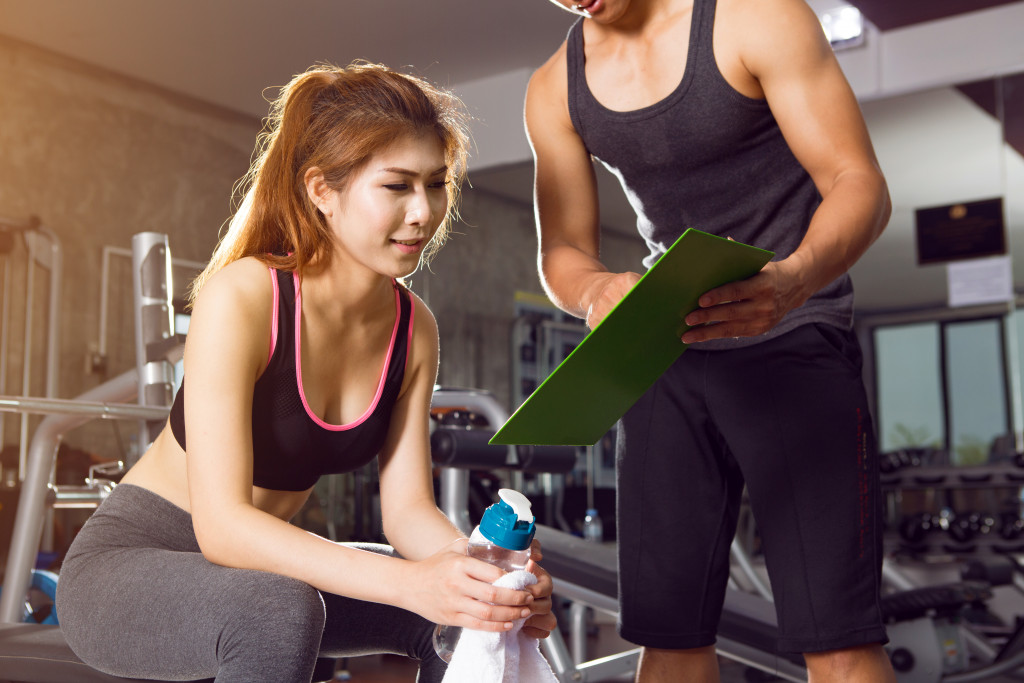 woman being shown by the trainer the next set of exercise she needs to do