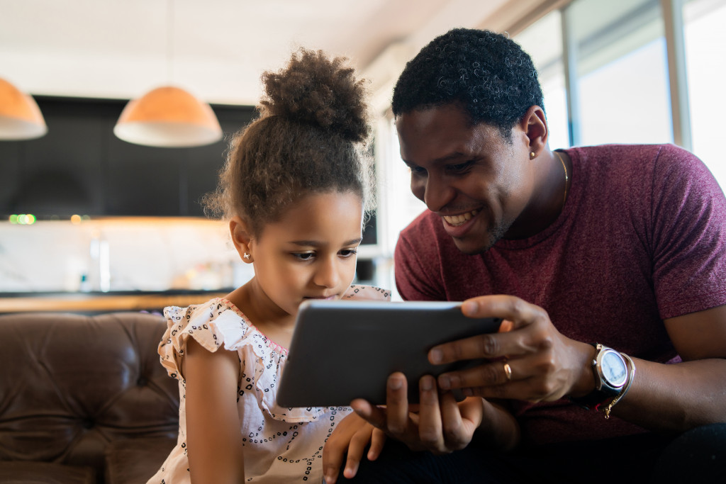 Father and his daughter using tablet at home