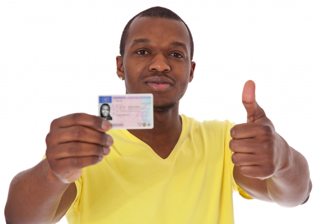 A man wearing yellow t shirt showing his business license and thumbs up