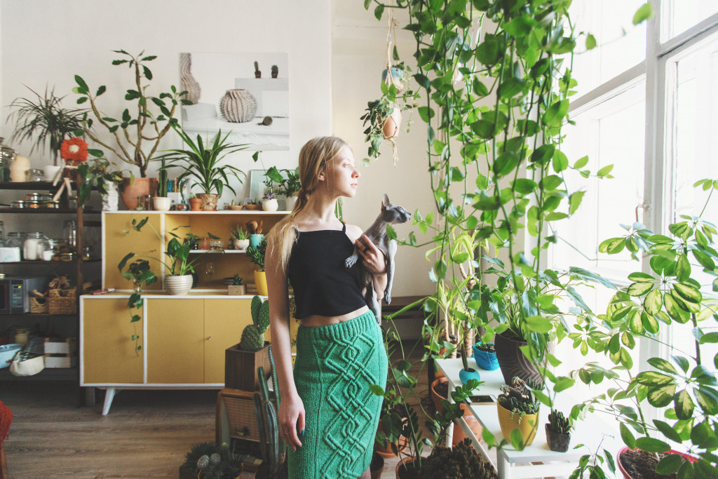 woman at home with plenty of plants and a cat
