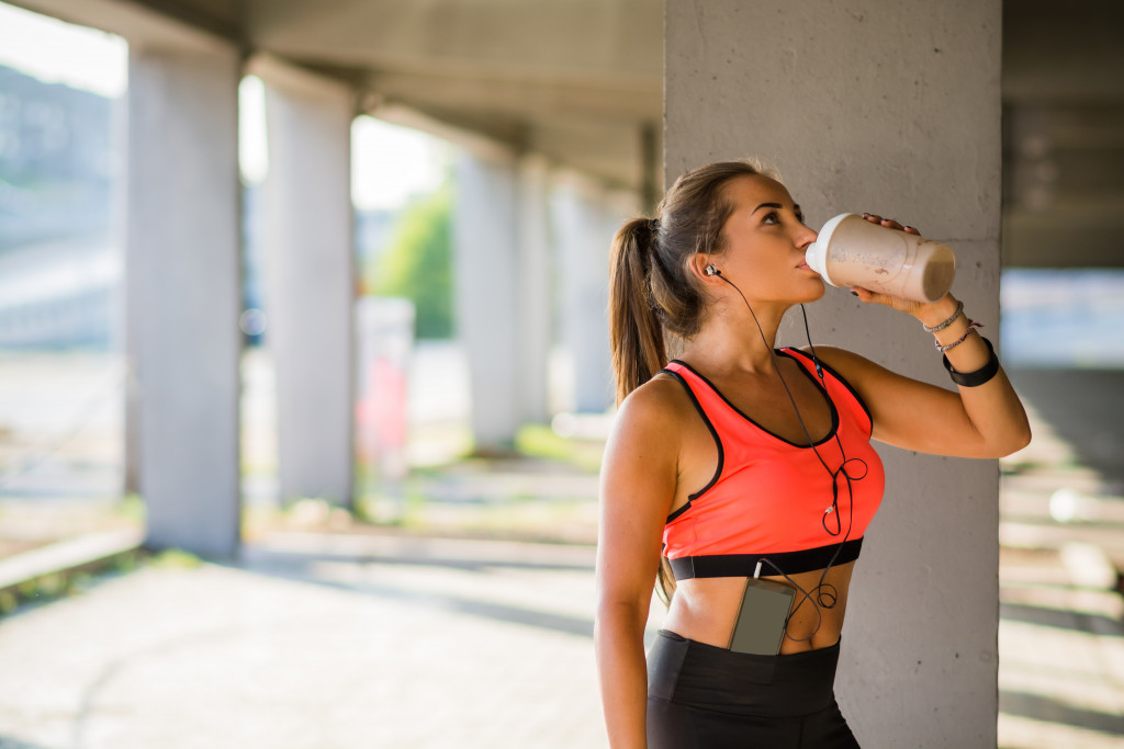 woman drinking protein shake after working out outdoors