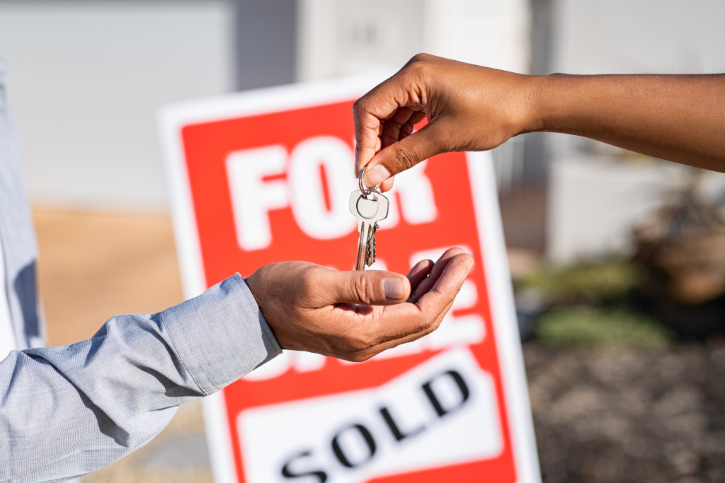 a person handing over the keys to a sold house to a businessman