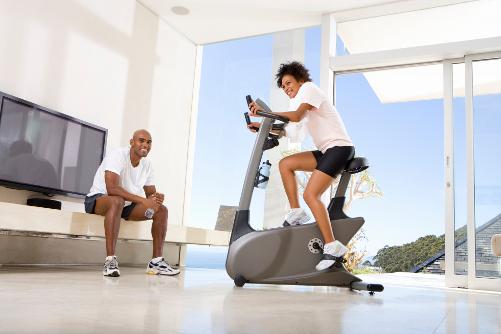 Young couple exercising at home on a stationary bike.