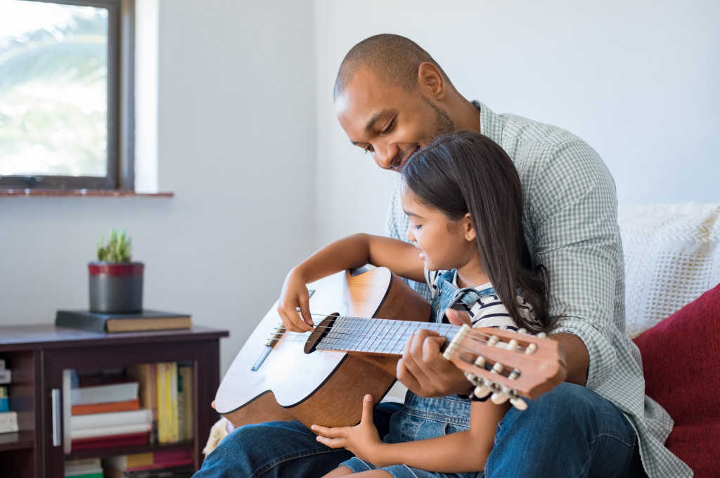 dad teaching his daughter guitar
