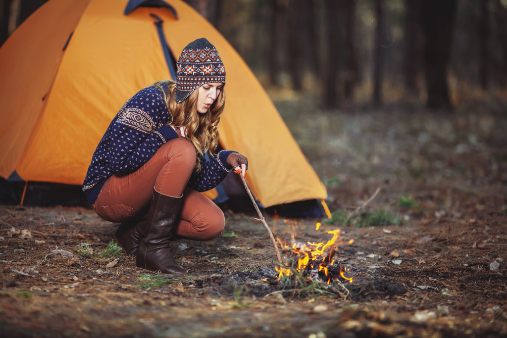 Young woman starting a fire while camping.